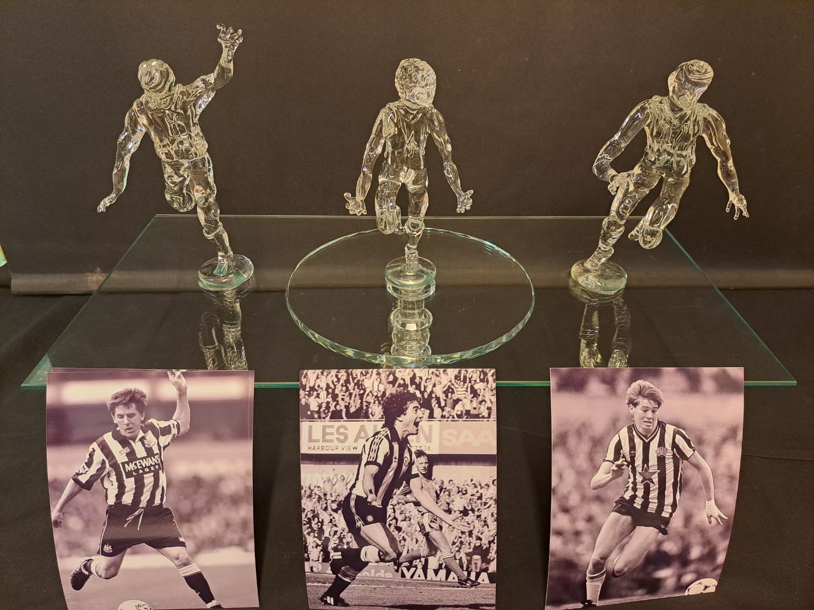 Glass football figures displayed with reference photos